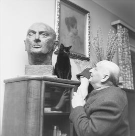 Artur Młodnicki z rzeźbą głowy i z kotem