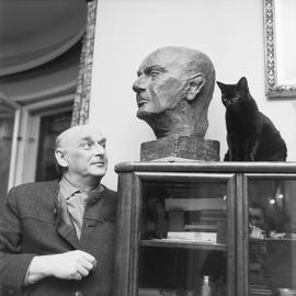 Artur Młodnicki z rzeźbą głowy i z kotem